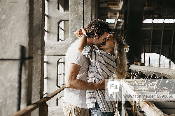 Junges Paar küsst sich in einem alten Bahnhof
