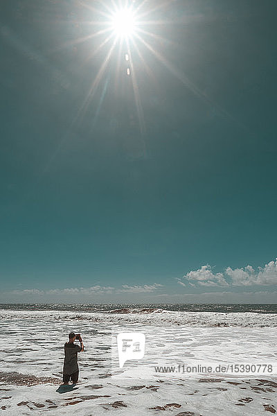 Spanien  Kanarische Inseln  Gran Canaria  Mann steht im Wasser  fotografiert mit Tablette