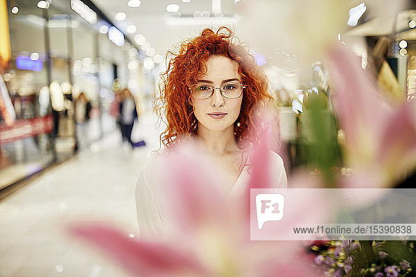 Porträt einer rothaarigen Frau hinter einer Blüte in einer Einkaufspassage
