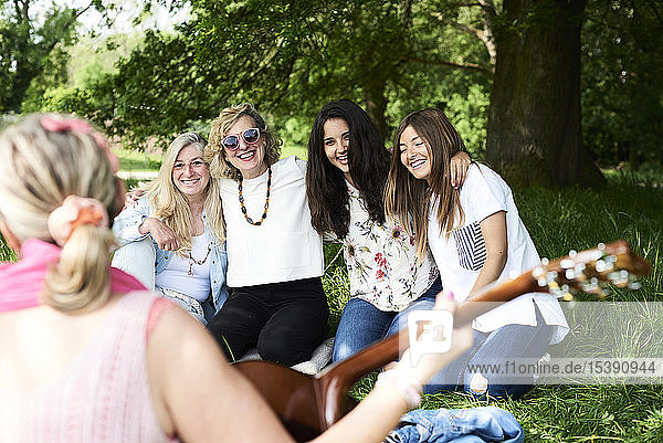 Group of women with guitar having fun at a picnic in park