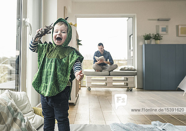 Happy boy in a costume playing with toy figure at home