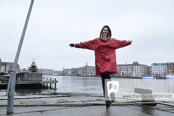Dänemark  Kopenhagen  glückliche Frau springt bei Regenwetter an die Uferpromenade