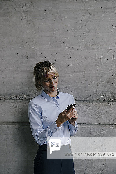 Blonde Geschäftsfrau benutzt Smartphone  liest Nachrichten