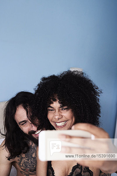 Happy affectionate young couple taking a selfie in bed