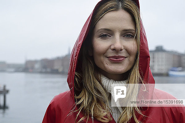 Dänemark  Kopenhagen  Porträt einer lächelnden Frau an der Uferpromenade bei Regenwetter