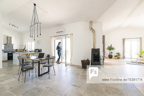 Woman standing in door frame of modern living room with fireplace