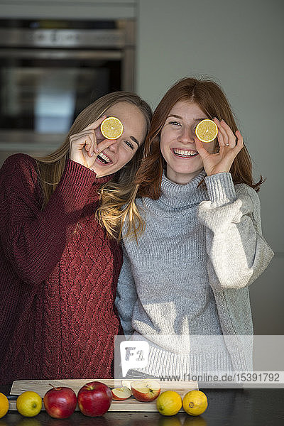 Zwei lachende Freunde halten sich Zitronenhälften vor die Augen