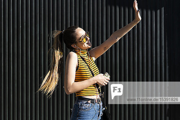 Glückliches Teenager-Mädchen mit Kopfhörern und Smartphone genießt den Sonnenschein