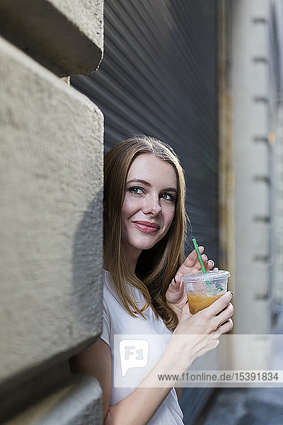 Junge Frau in der Stadt trinkt Kaffee zum Mitnehmen