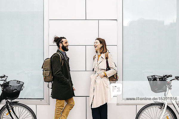 Man and woman with e-bikes standing at a building talking
