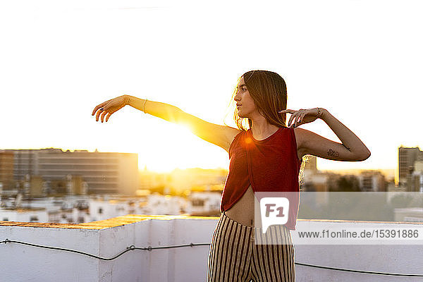 Anmutiges Teenager-Mädchen bewegt sich bei Sonnenuntergang auf der Dachterrasse in der Stadt