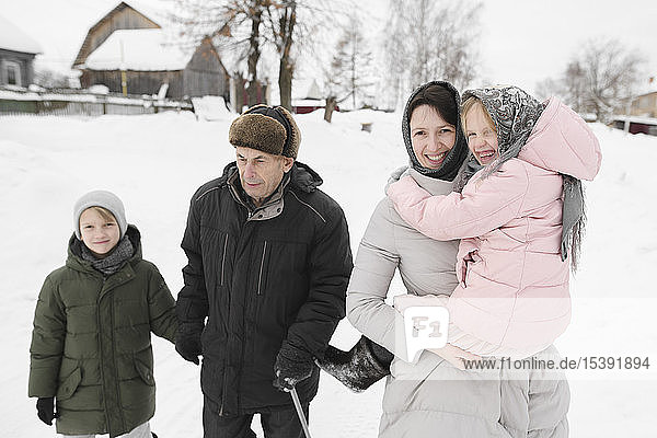 Grandfather strolling together with daughter and grandchildren in winter