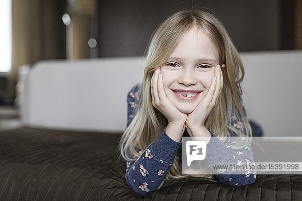 Porträt eines lächelnden kleinen Mädchens mit Zahnlücke und Kopf in den Händen