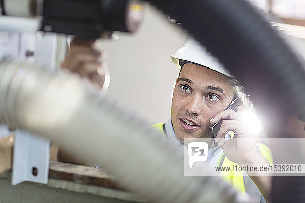 Ein Techniker bei der Arbeit telefoniert mit einem Mobiltelefon