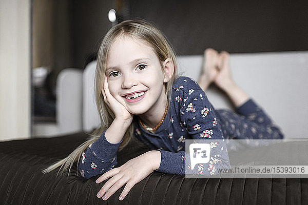 Portrait of smiling little girl with tooth gap relaxing on couch at home
