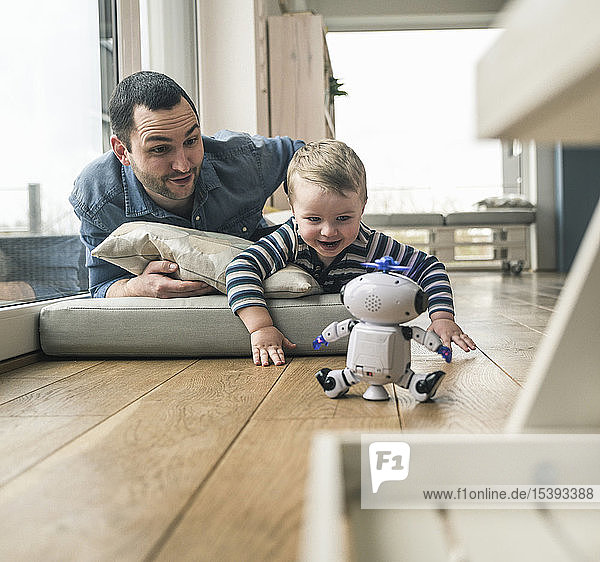 Excited father and son lying on a mattress at home watching a toy robot