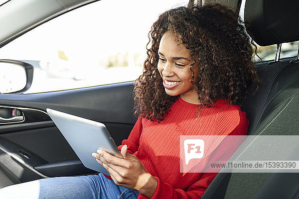 Lächelnde junge Frau mit Tablette im Auto
