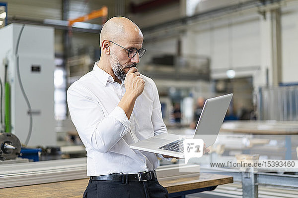 Focused businessman using laptop in factory