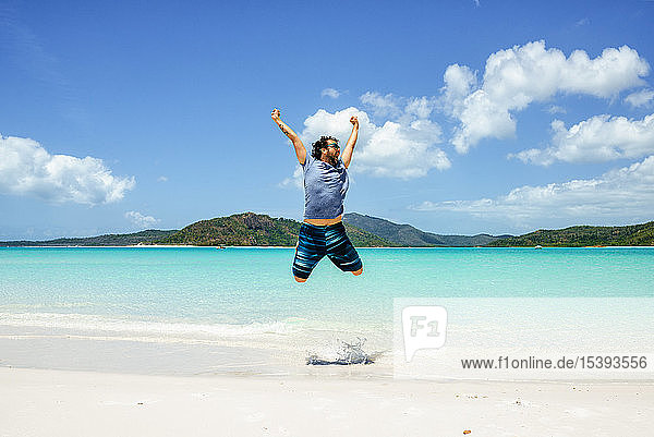 Australia  Queensland  Whitsunday Island  carefree man jumping at Whitehaven Beach