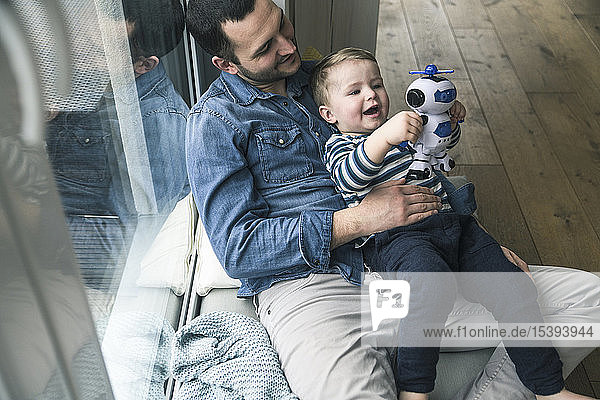Father and son playing with a toy robot at home