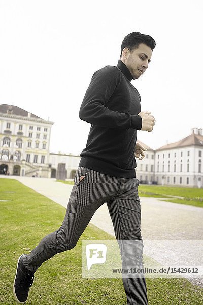 Young man running in front of aristocratic Nymphenburg Palace  touristic sight  in Munich  Germany.