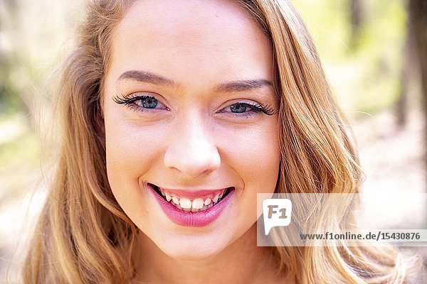 Portrait of a pretty 15 year old blond girl  smiling directly at the camera  outdoors.
