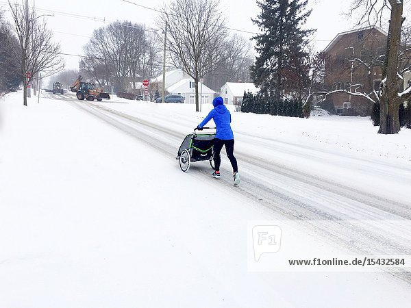A woman pushes a baby carriage on a snow covered street Canada.