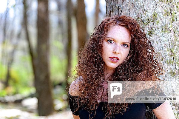 Portrait of a beautiful redheaded woman looking directly at the camera outdoors.