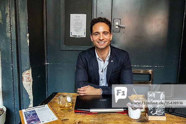 Berlin Germany. Young Adult & Gay Professional working with his laptop computer and smartphone inside a coffee place to help out his customers with their online marketing and seo.
