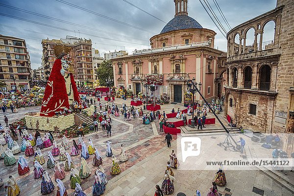 Fallas festival. Falleros and Falleras in traditional dress. Parade to the Plaza de la Virgin in order to make an offering of flowers to Our Lady of the Forsaken the Patron Saint of Valencia. The celebration takes place from 4 pm until past nightfall. With all of the bunches of flowers given by the falleras to the Virgin an impressive 15 metre-high tapestry is formed on the main façade of the Basilica and a mantle is made for the Virgin. Valencia. Valencian Community. Spain.