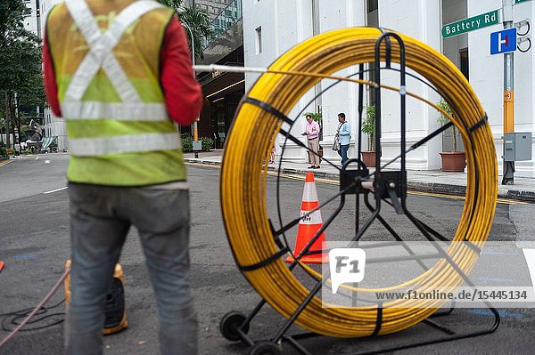 Singapore Republic of Singapore Asia - A worker is laying cables on a road in the central business district.