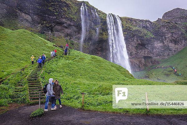 Tourists next to Seljalandsfoss waterfall in South Region of Iceland.