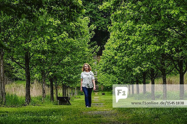 Dover Stone Church  New York  USA A woman walking along a tree-lined alley after the rain.