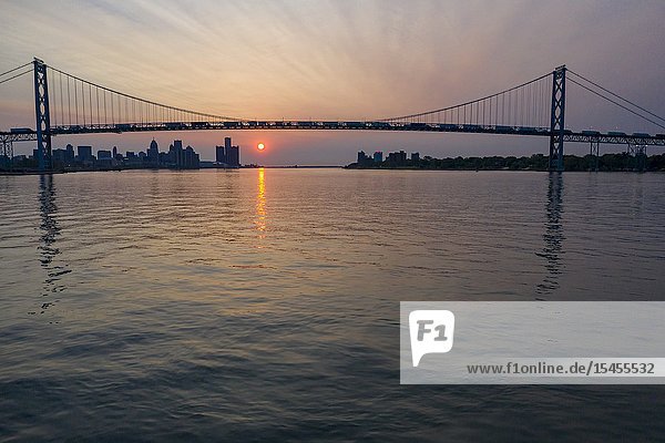Detroit  Michigan - Sunrise over the Detroit River. The Ambassador Bridge links the United States (left) and Canada.