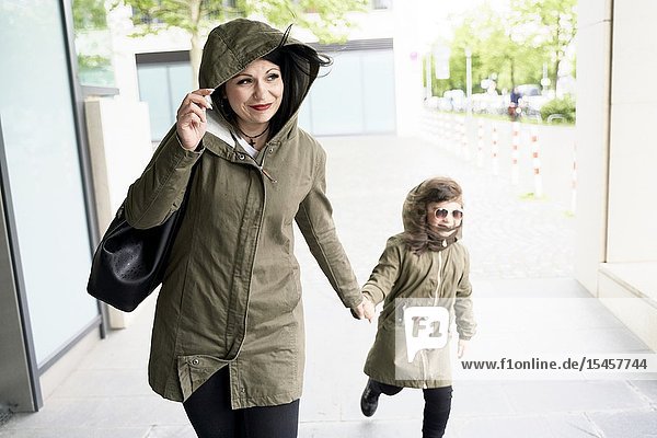 Confident single mother walking with daughter on hand in city optimism