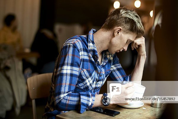 Young troubled man taking break in café
