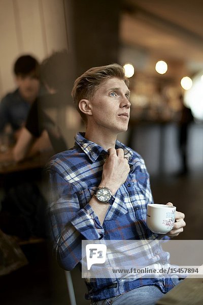 Young thoughtful man taking break in coffee shop