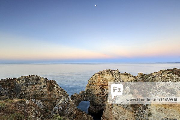 The sky turns pink at dawn on Ponta Da Piedade Lagos Algarve Portugal Europe.