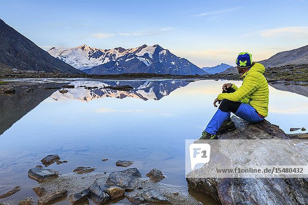 Hiker looks at Pizzo Tresero and Punta San Matteo from Cedec lake Stelvio National Park Valtellina Sondrio province Lombardy Italy.
