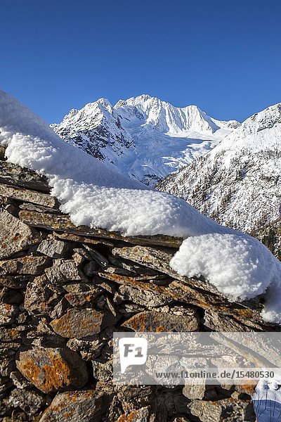 Stone hut covered with snow with Monte Disgrazia on background Alpe dell'Oro Valmalenco Valtellina Lombardy Italy.
