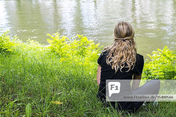 Utrecht Netherlands. Young lesbian woman pondering the romance with her new girlfriend while sitting alongside a canal.