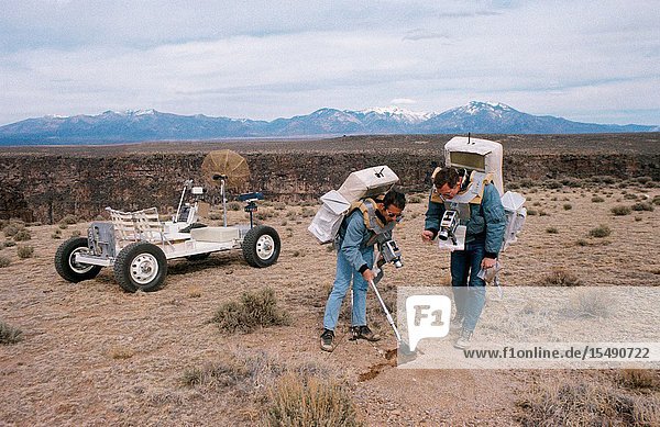 Two members of the prime crew of the Apollo 15 lunar landing mission collect soil samples during a simulation of lunar surface extravehicular activity in the Taos  New Mexico area. Astronaut James B. Irwin  lunar module pilot  is using a scoop. Astronaut David R. Scoot (right)  commander  is holding a sample bag. On the left is a Lunar Roving Vehicle trainer.