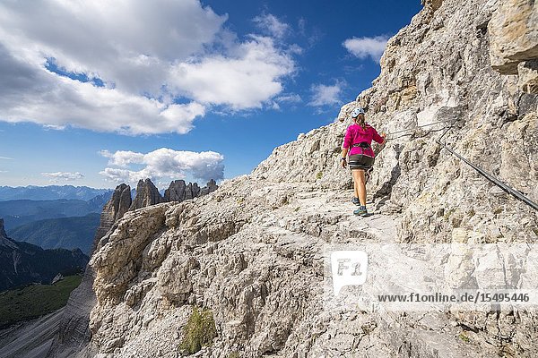 Young woman walking on the via ferrata that leads to the summit of Mount Paterno, in summer. Sesto Dolomites, Trentino Alto Adige, Italy.