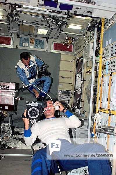 Cosmonaut Vladimir Dezhurov Expedition Three flight engineer operates a video camera in the Zvezda Service Module. In the background cosmonaut Mikhail Tyurin flight engineer is visible with a photographic camera. Tyurin and Dezhurov represent Rosaviakosmos.