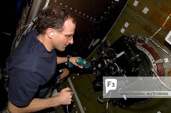 Astronaut Donald R. Pettit Expedition Six NASA ISS science officer runs a drill while looking through a camera mounted on the nadir window in the Destiny laboratory on the International Space Station (ISS). The device is called a barn door tracker. The drill turns the screw which moves the camera and its spotting scope.