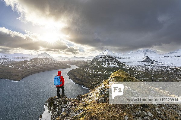 Hiker standing on peak over Funningur fjord (Eysturoy island Faroe Islands Denmark) (MR).