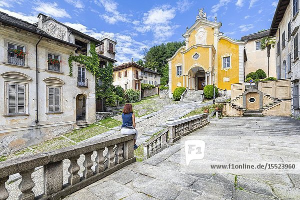 A tourist is looking the church of Santa Maria Assunta (Orta San Giulio Lake Orta Novara province Piedmont Italy Europe) (MR).