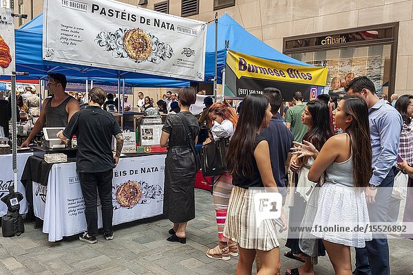 Tourists and office workers line up at Pasteis De Nata in The Outpost of the Queens Night Market located in Rockefeller Plaza in New York on Tuesday July 30 2019. The marketplace features ethnic and artisanal foods by small entrepreneurs all of whom are regulars at the Queens Night Market. Nine vendors will encamp in the plaza Monday through Thursday for three weeks. (© Richard B. Levine).