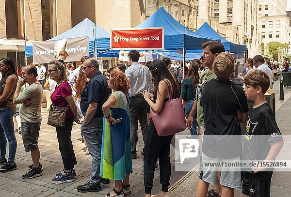 Tourists and office workers flock to The Outpost of the Queens Night Market located in Rockefeller Plaza in New York on Tuesday July 30 2019. The marketplace features ethnic and artisanal foods by small entrepreneurs all of whom are regulars at the Queens Night Market. Nine vendors will encamp in the plaza Monday through Thursday for three weeks. (© Richard B. Levine).