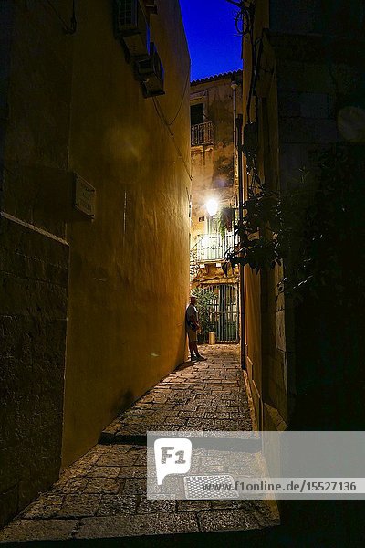 Syracuse Sicily Italy A pedestrian on the back streets of Ortygia island at dawn.